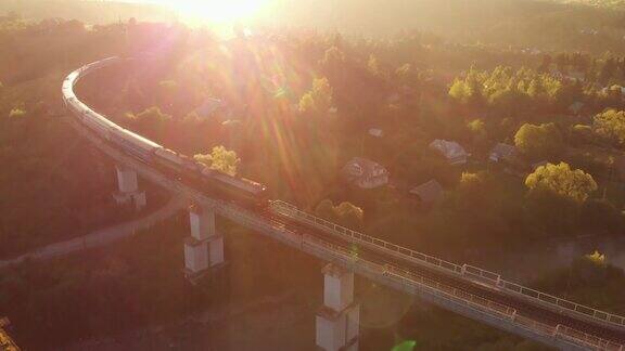 一列火车在日落时穿过一座美丽的石桥的航拍照片