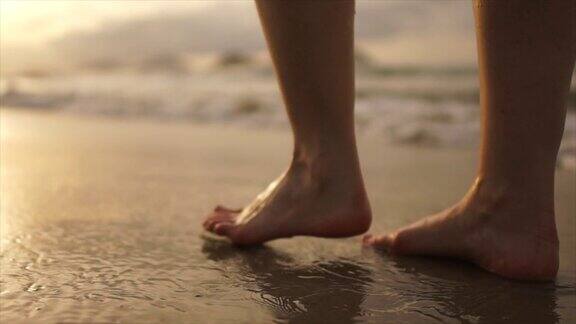 女人赤脚走在日落的海滩上