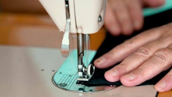 缝纫机的针在动缝纫机针的特写快速上下移动裁缝在缝纫车间缝黑色的布料缝纫织物的过程
