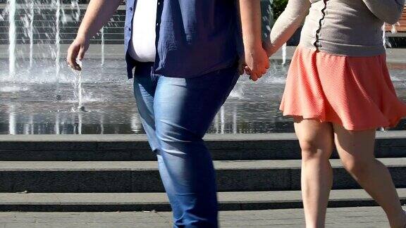 胖男人和胖女人手牵着手一起走在城市里浪漫的户外约会