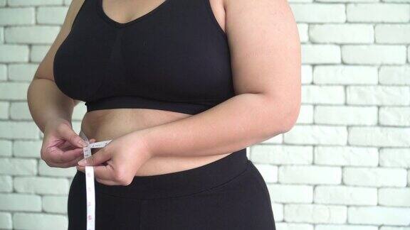 侧面图:泰国超重妇女用卷尺测量她的腹部
