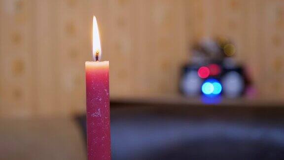 燃烧的红色蜡烛与明亮的移动火焰在模糊的灯光背景