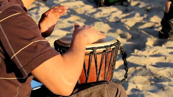 在海滩上弹奏Djembe鼓的年轻人