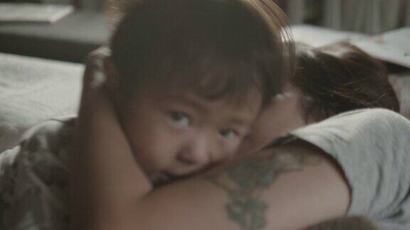 亚洲母亲拥抱婴儿的女儿在床上