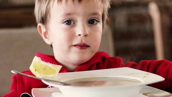 小男孩在桌子上吃汤和面包