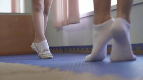 一个小女孩在体操鞋的特写踮着脚尖试图与教练进行练习