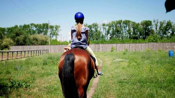 后视镜小女孩戴着防护头盔骑着一匹棕色的马