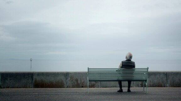 一位老人坐在海边的长椅上特写