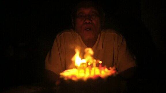 年长的亚洲男人吹生日蜡烛