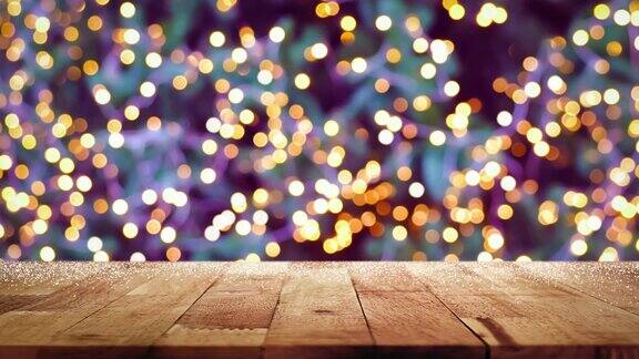 木质桌面与闪烁的装饰灯bokeh在圣诞树在晚上的背景