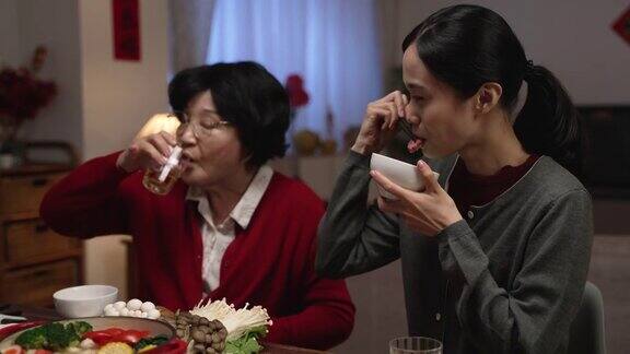 快乐的亚洲媳妇在和她穿着红色衣服的老母亲聊天他们在家里享受丰盛的年夜饭