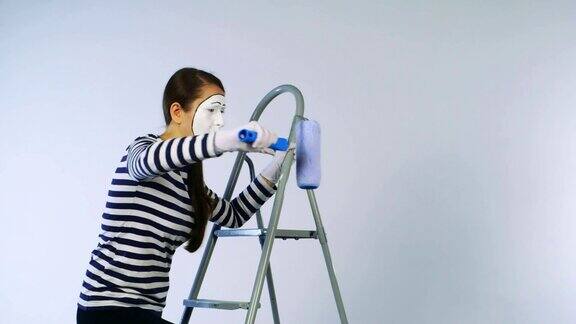 一个女人站在梯子上做哑剧画着看不见的墙