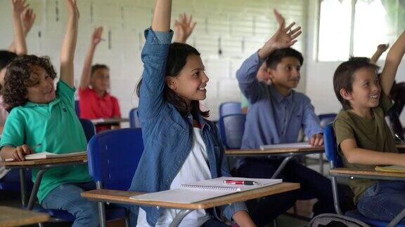 课堂上一群孩子兴奋地举手回答问题
