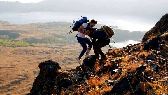 两位背包客互相帮助攀登山峰