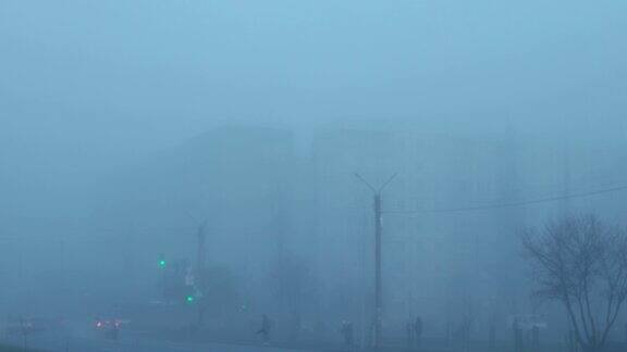 在城市街道的十字路口运行的交通灯行人在浓雾中沿着人行道行走