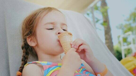 一个快乐的小女孩享受着暑假躺在海边的沙发上吃着美味的冰淇淋