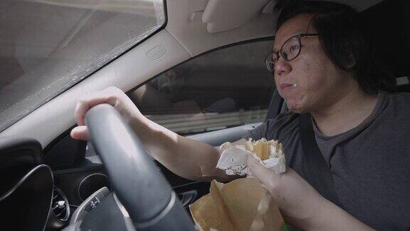 男人一边开车一边吃汉堡