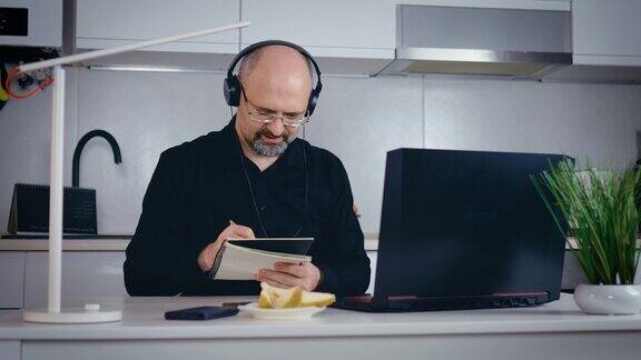快乐的大胡子商人工作在笔记本电脑从家庭办公室男性高管使用电脑远程学习浏览网页召开虚拟会议写笔记