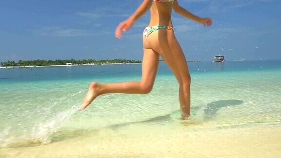 特写:女人完美的身体在海滩冲浪跑步