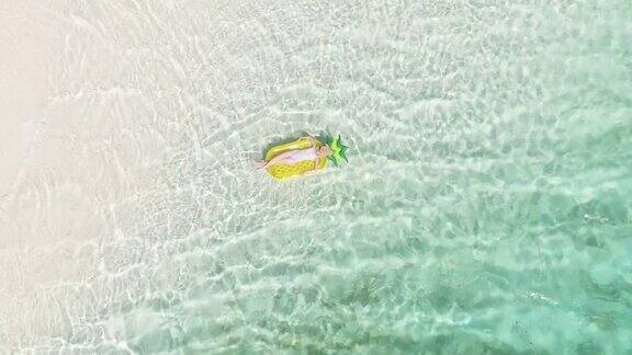 空中的女孩漂浮在清澈的绿松石水放松在充气水果圈在热带岛屿天堂文本拷贝的空间