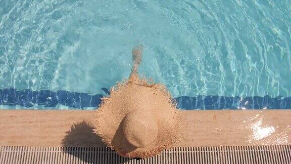 戴着草帽的陌生女子在蓝色的泳池里放松俯视图慢动作