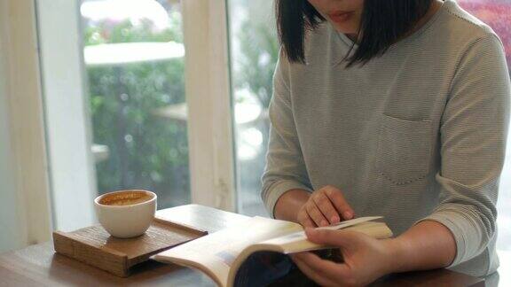 一个女人一边看书一边在咖啡馆喝咖啡