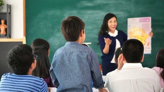 男生站在课堂上举手回答问题的后视图学生举手向讲师提问