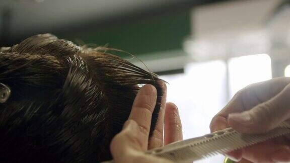 理发师用剪刀剪年轻人的头发的特写镜头慢动作