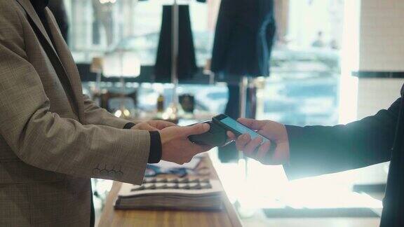 一名男子在男装店里用智能手机付款