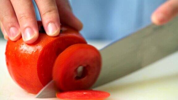 在厨房里切西红柿的女人年轻的亚洲家庭主妇将生番茄切成薄片为食物和晚餐做准备家庭烹饪