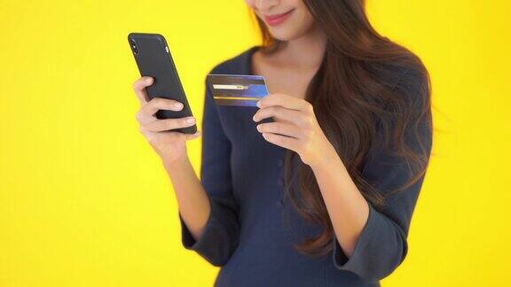 年轻的亚洲女性使用智能手机和信用卡进行网上购物