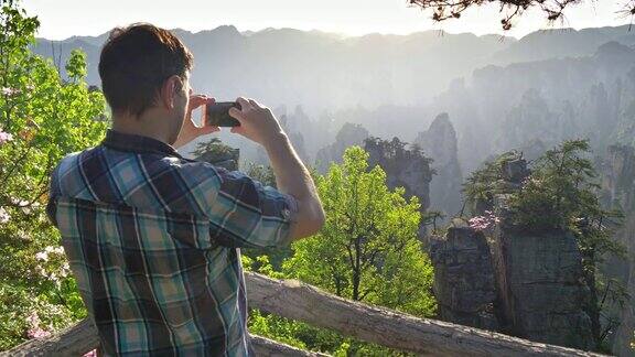 在一个阳光明媚的日子里一名游客在武陵源用他的智能手机拍摄悬崖峭壁的风景张家界中国UHD
