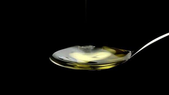 橄榄油倒在勺子上的黑色背景