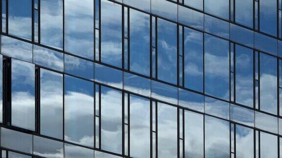 蓝色的夏日天空云朵反射在办公大楼的玻璃幕墙上
