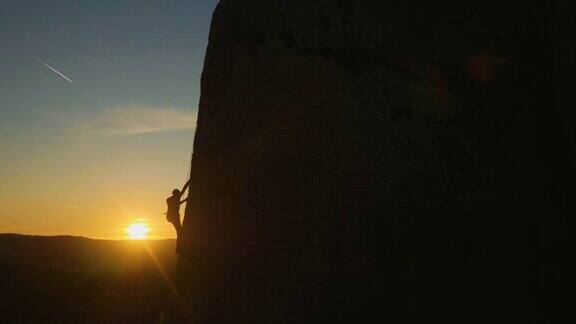 攀岩爱好者日落时分在山峰上攀岩