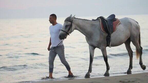 日落时分一个男人和他的马在海滩上消磨时光