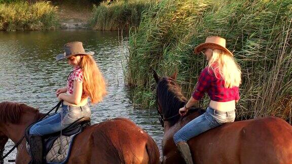 两个骑马的女孩在湖里给马洗澡