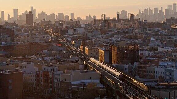 从住宅区远眺布鲁克林市中心和曼哈顿傍晚一列火车沿着默特尔大道沿着高架地铁开往布鲁克林市中心无人机视频与前摇摄像机运动