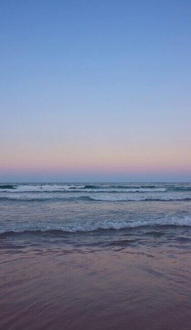 海洋海滩日落与彩色天空云和海浪冲刷海沙垂直4K视频