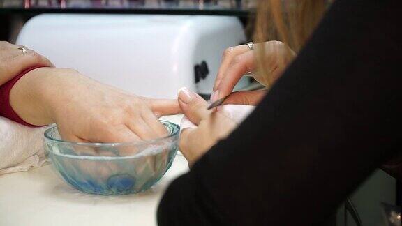一个女人在一个美甲沙龙接受一个美容师用指甲锉修指甲的特写镜头正在修指甲的女人美容师给顾客锉指甲