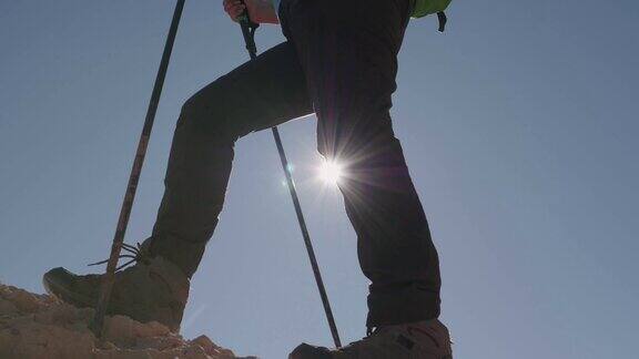 穿靴子的脚登山运动员游客爬上山岩太阳照过腿