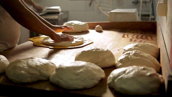 在面包房的厨房里面包师用面团制作小面包