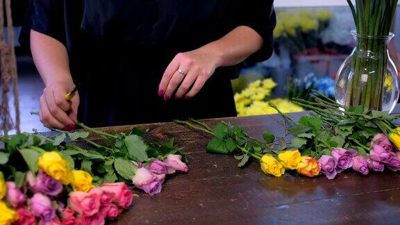 花店女店员准备鲜花束切玫瑰刺在店里特写手