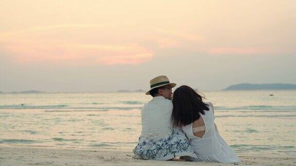 4K的亚洲情侣一起坐在沙滩上欣赏夏日夕阳