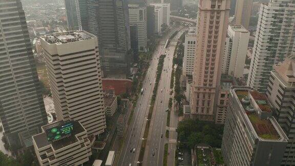 在印度尼西亚的雅加达在被摩天大楼包围的多车道高速公路上不断上升的空中镜头倾斜到汽车交通的头顶视图