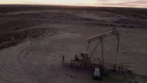 从右到左的缓慢视差无人机拍摄的水力压裂油和天然气泵千斤顶工作在黄昏西德克萨斯油田