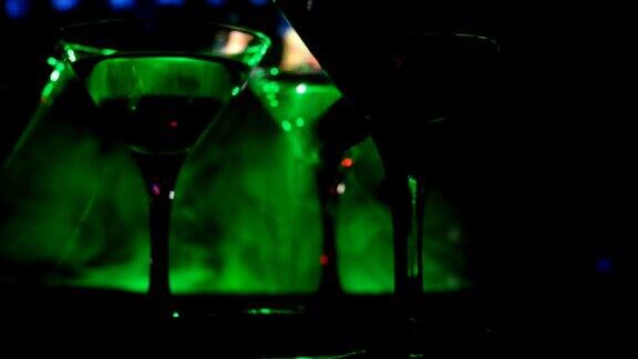 酒精饮料倒入马提尼杯的瓶子几杯著名的鸡尾酒马提尼在酒吧与黑暗色调朦胧的背景和迪斯科灯光俱乐部饮料有选择性的重点滑块拍摄