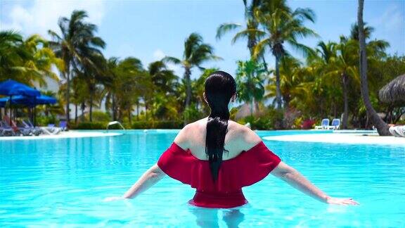 美丽的年轻女子在游泳池里放松豪华酒店室外泳池里的快乐女孩