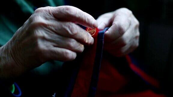 一个非常老的女人缝合扣子的手的特写