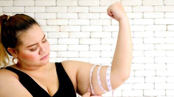 一个不幸的超重妇女用测量尺测量手臂的特写